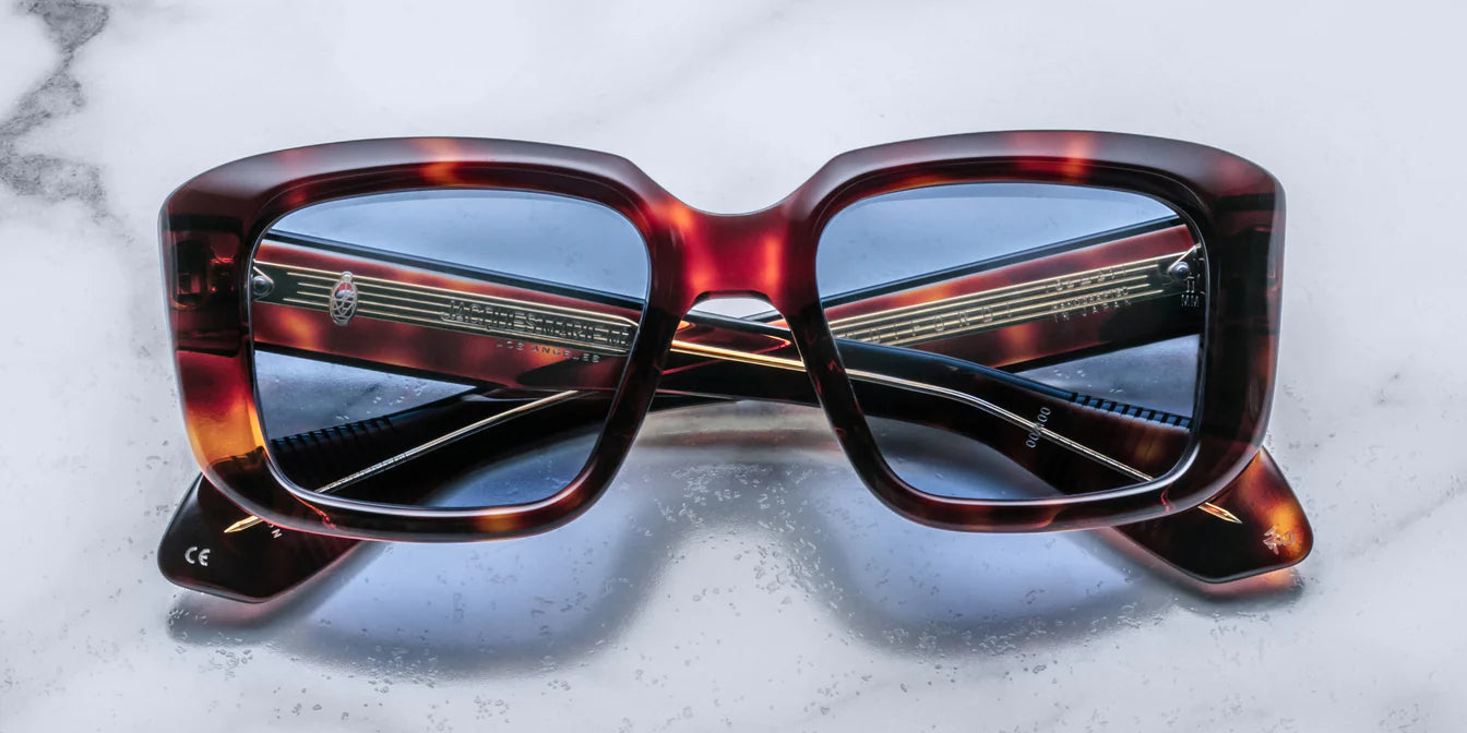 A pair of sunglasses with a Havana brown patterned frame on a marble surface.