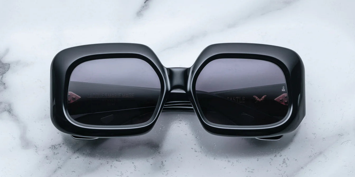 A pair of black, rectangular, '70s-inspired sunglasses with a marble background.
