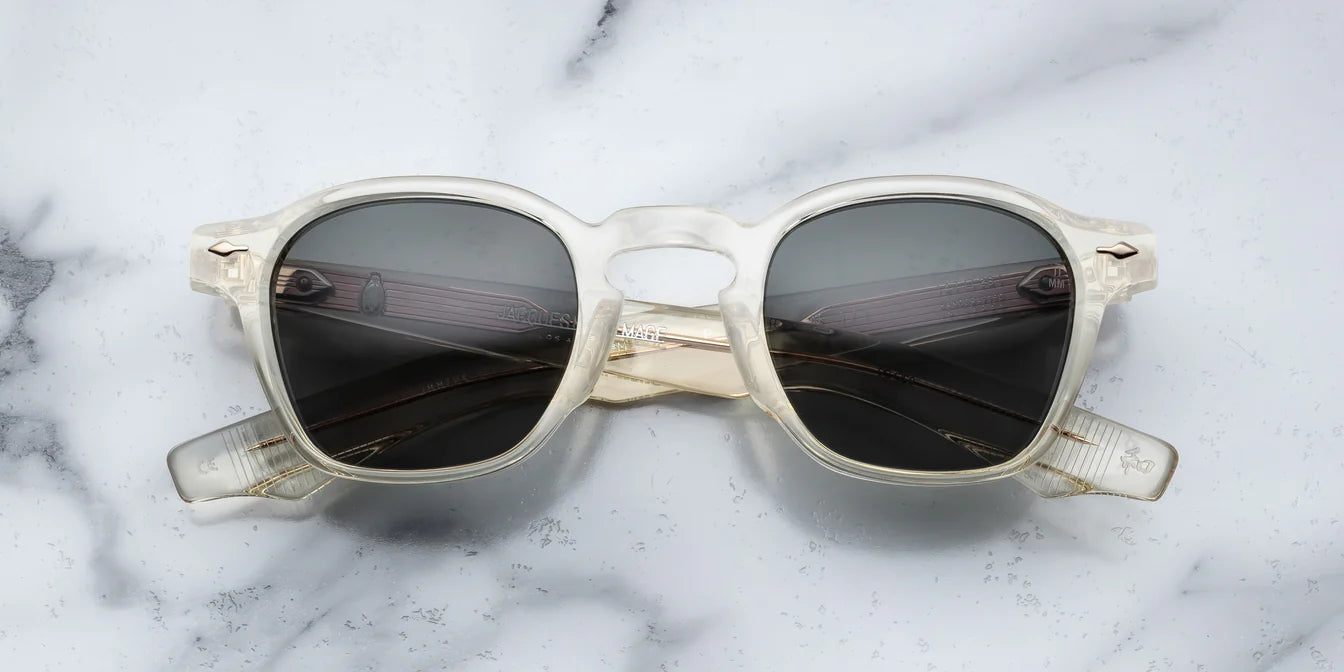 A pair of sunglasses with a distinctive frame, sculptural temples, and a sophisticated silhouette. The frame is notable for its slim lines in champgne