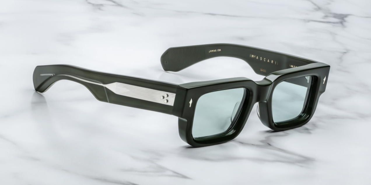 A pair of rectangular, dark green sunglasses with custom double-laminated temples and wirecores, on a marble surface. side view