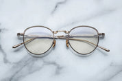 Round eyeglasses with gold frame on a marble surface