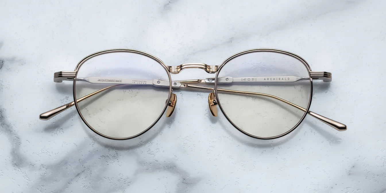 Round eyeglasses with gold frame on a marble surface
