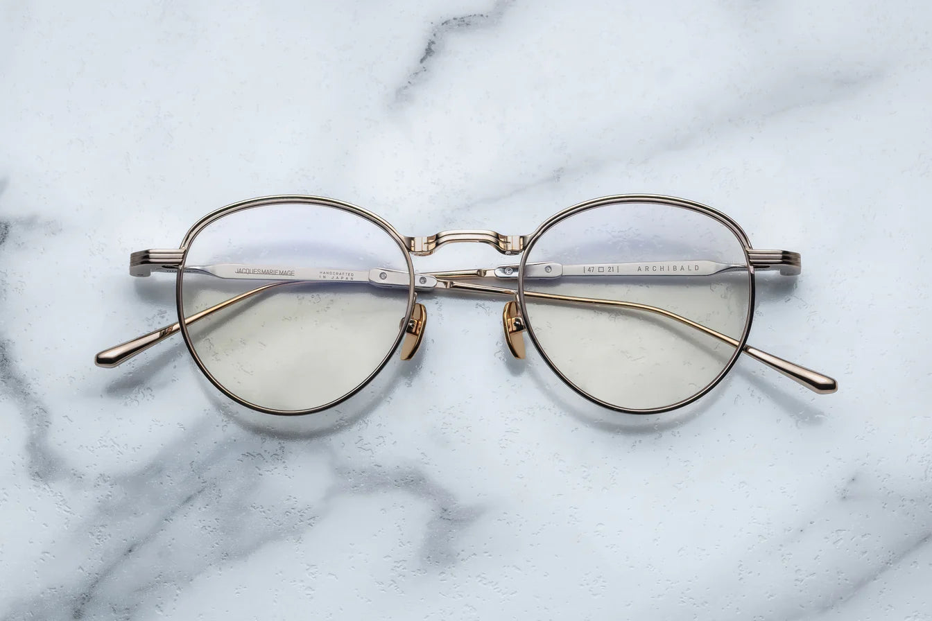 Round eyeglasses with gold frame on a marble surface