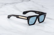 Black sunglasses with blue lenses and embellis on a marble surfaceed temples