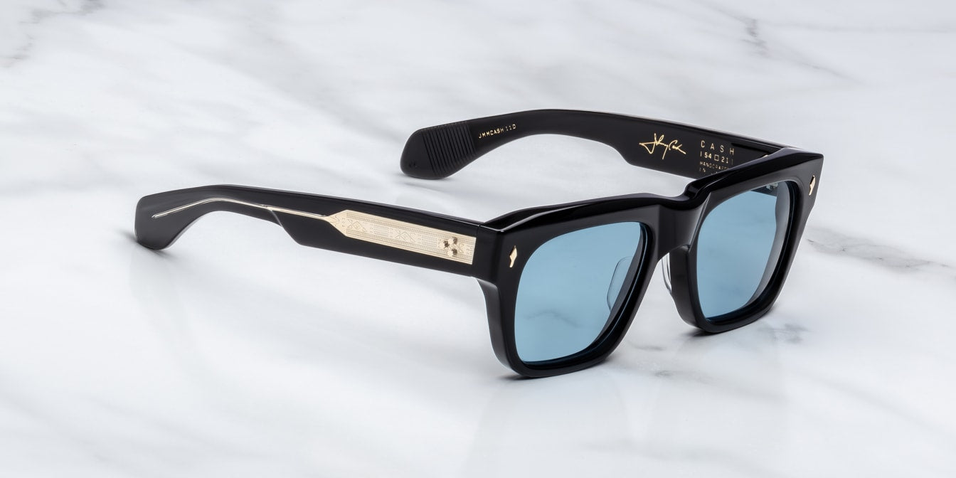 Black sunglasses with blue lenses and embellis on a marble surfaceed temples