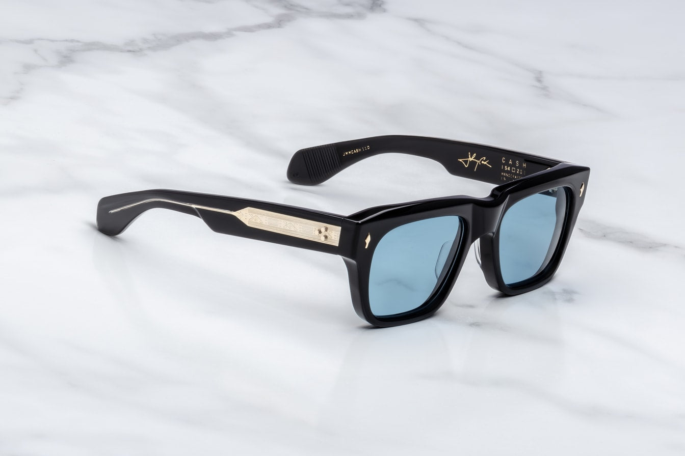 Black sunglasses with blue lenses and embellis on a marble surfaceed temples