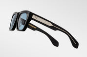 Black sunglasses with gold accents on a light gray background