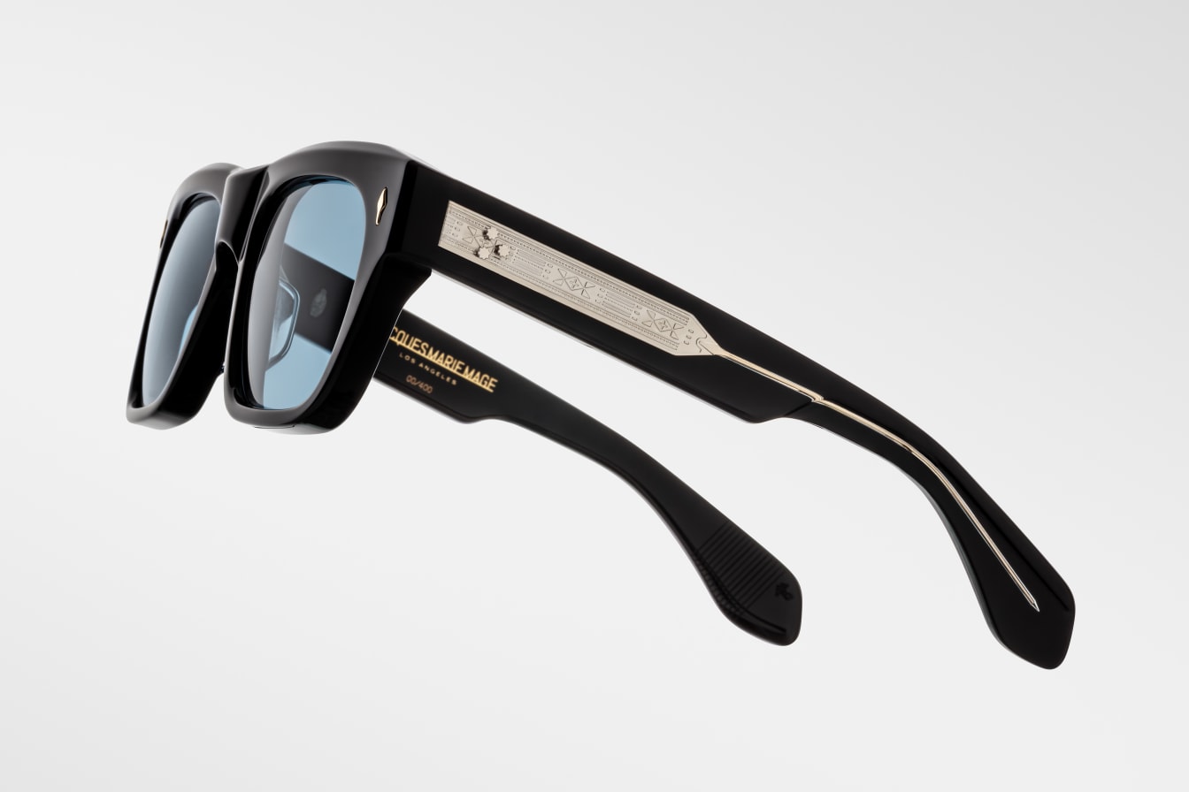Black sunglasses with gold accents on a light gray background