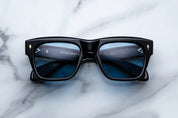 Black sunglasses with blue lenses on a marble surface