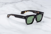 Black sunglasses with green lenses on a light gray background