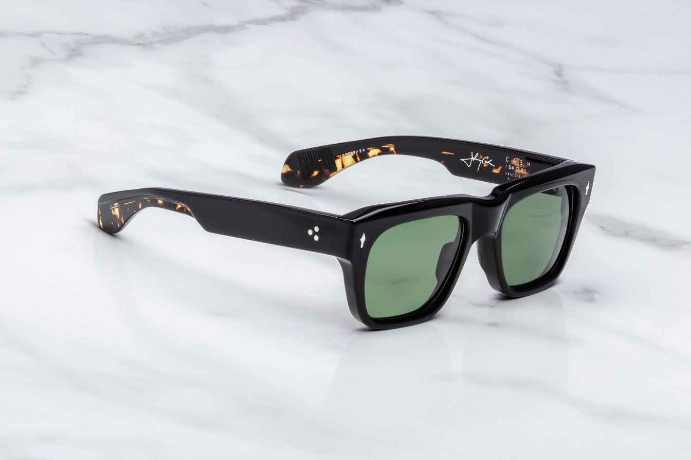 Black sunglasses with green lenses on a light gray background