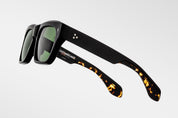 Black sunglasses with black tortoiseshell arms on a light gray background