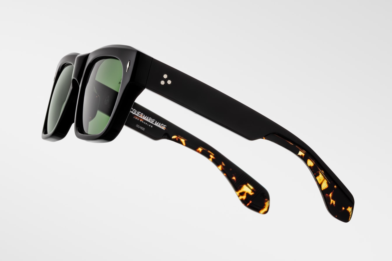 Black sunglasses with black tortoiseshell arms on a light gray background