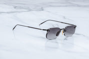 Slide view of rimless sunglass with black titanium temples