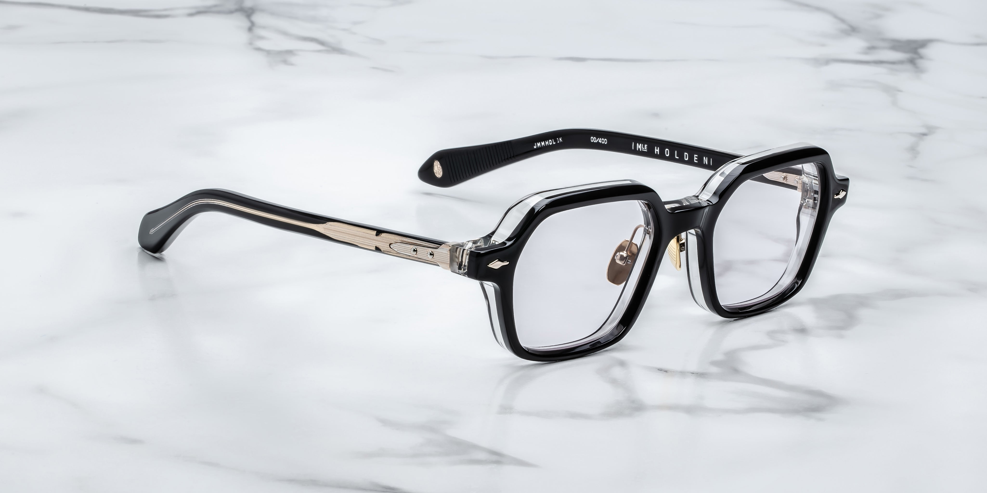 side view of JM holden frame black with clear acetate on the back and light gold detail on temples