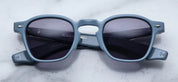 A pair of sunglasses with a distinctive frame, sculptural temples, and a sophisticated silhouette. The frame is notable for its slim lines.