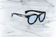 A pair of sunglasses in black, placed on a marble surface. side view