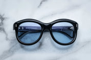 A pair of sunglasses in black, placed on a marble surface.