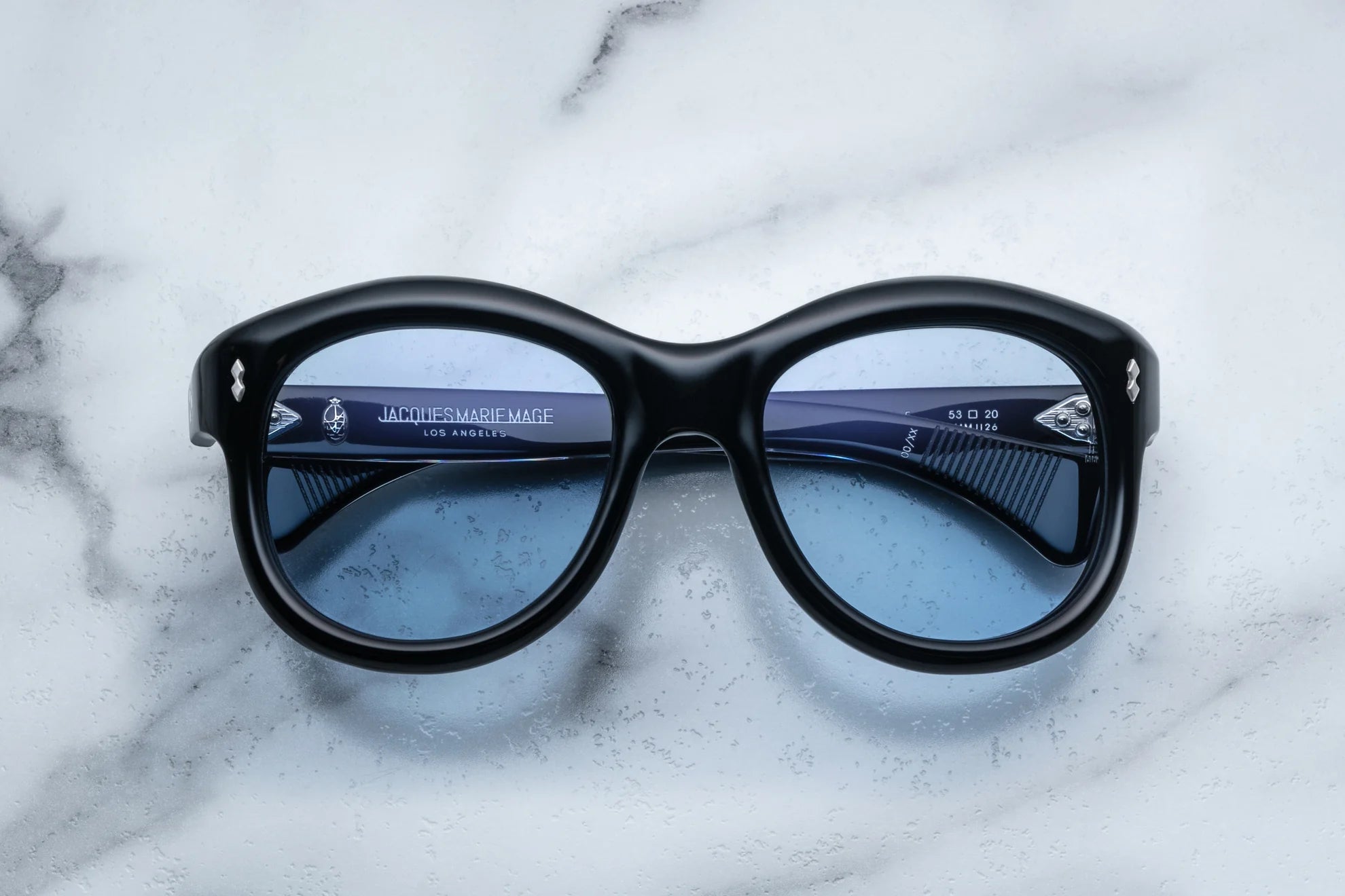 A pair of sunglasses in black, placed on a marble surface.