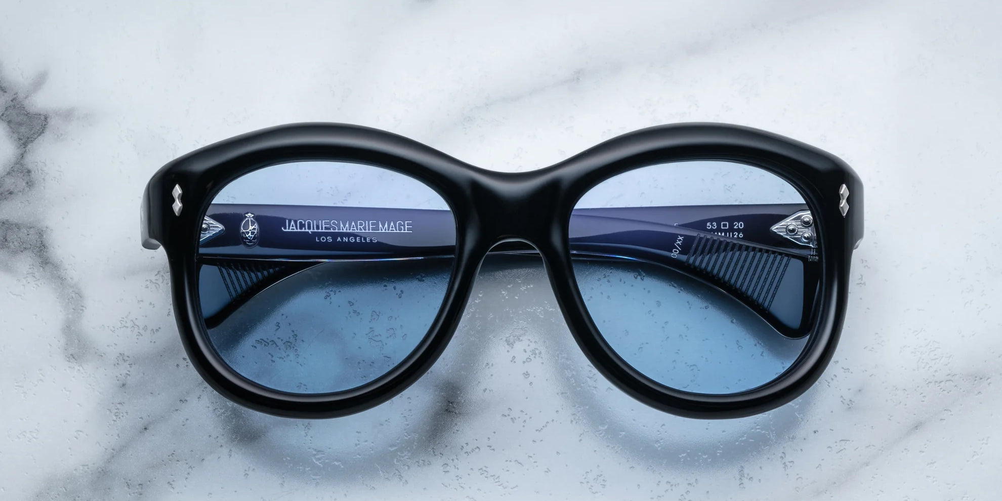 A pair of sunglasses in black, placed on a marble surface.