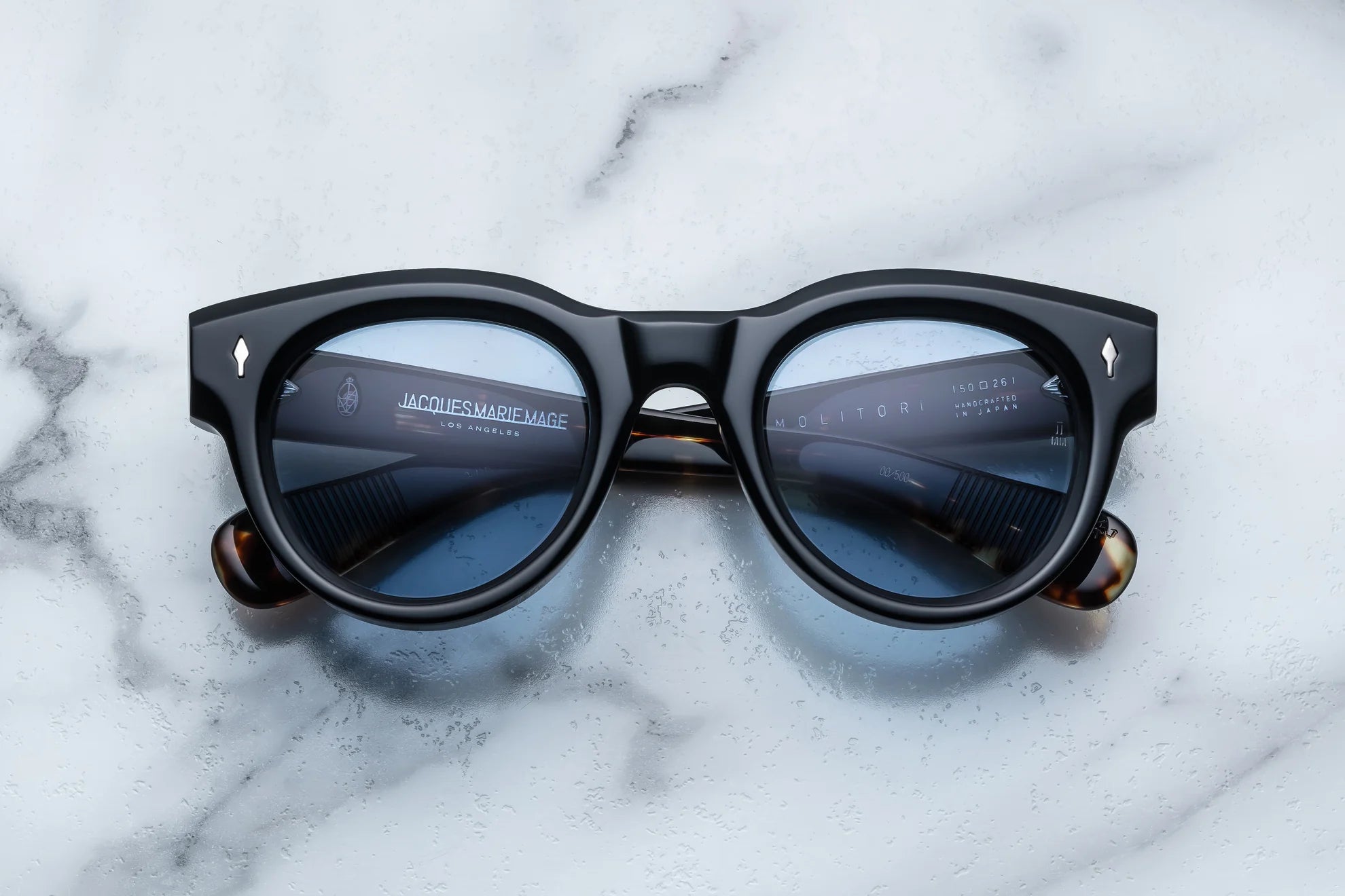 round sunglass in black with silver arrow pin motif on the sides