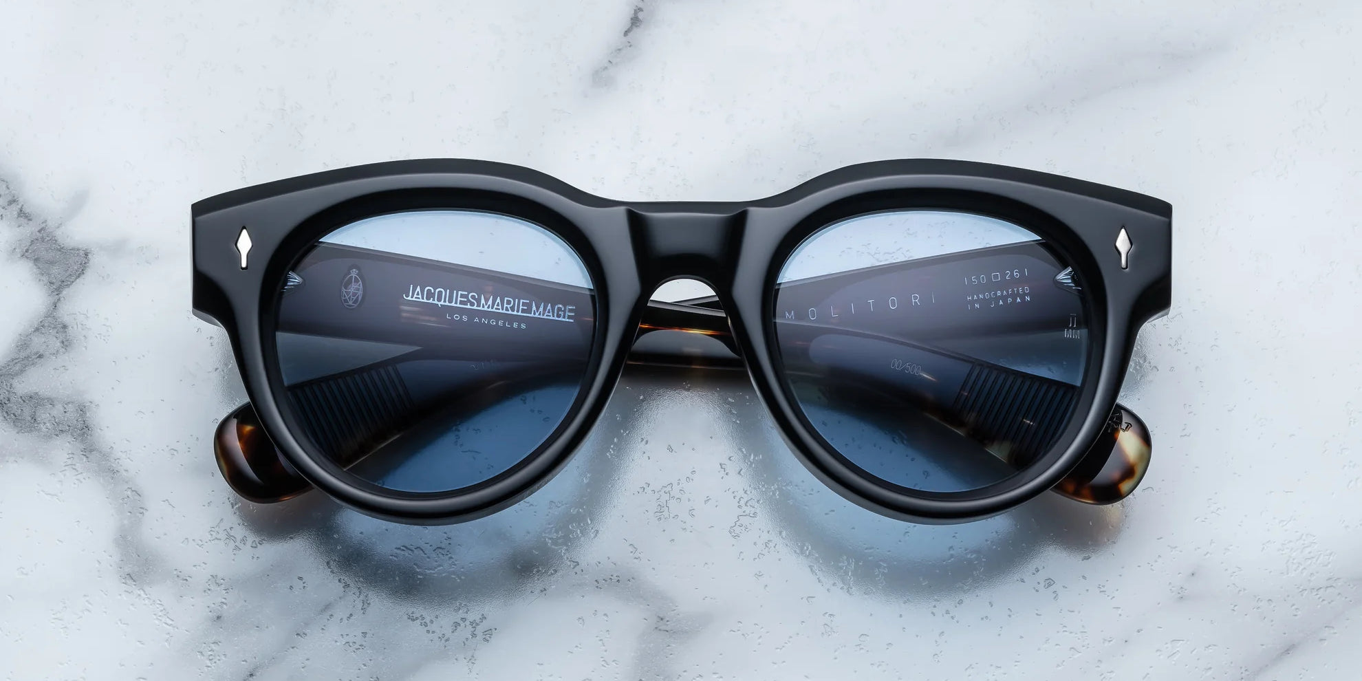 round sunglass in black with silver arrow pin motif on the sides