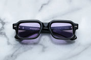 Black sunglasses with purple lenses on a marble surface