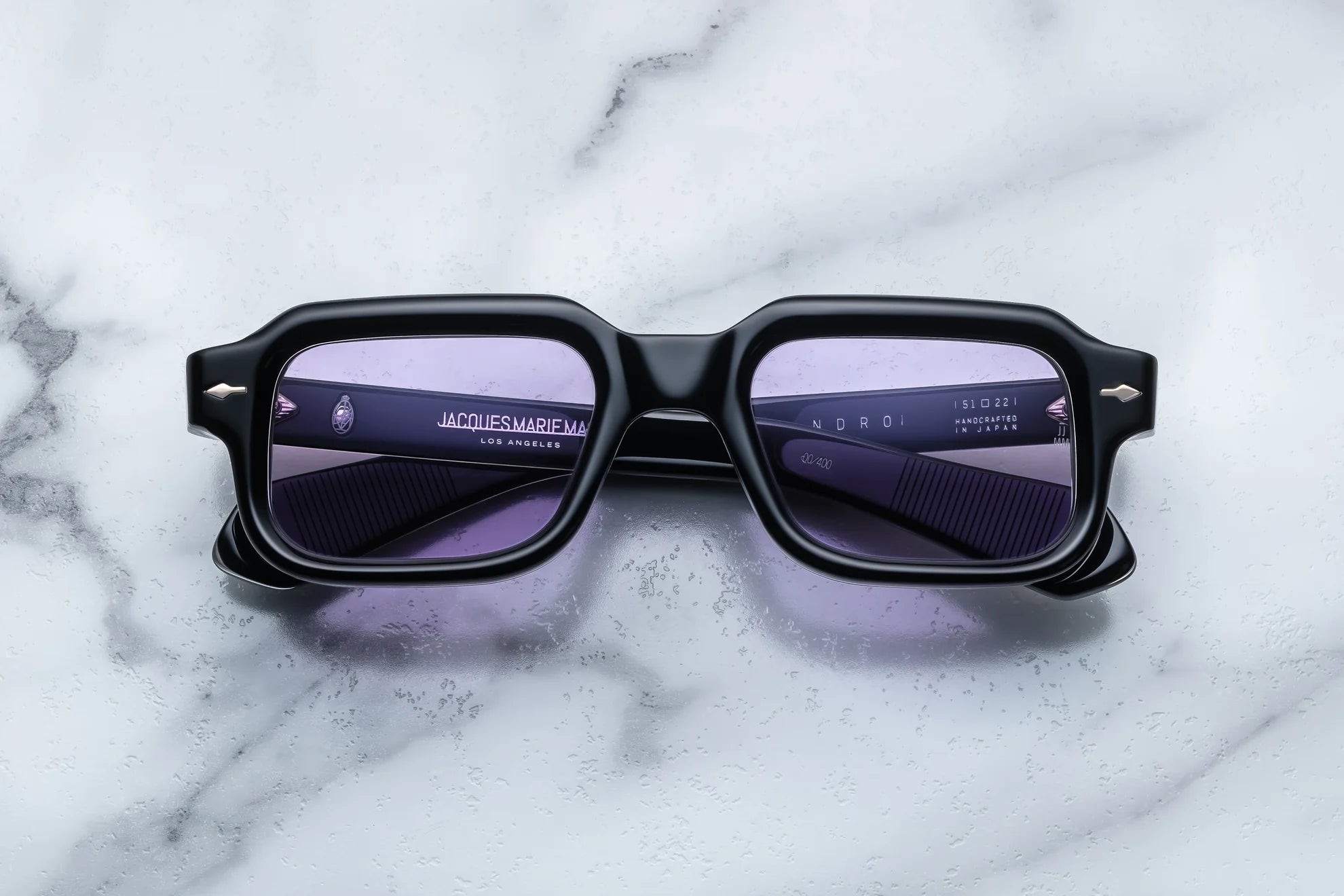 Black sunglasses with purple lenses on a marble surface