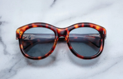 A pair of sunglasses with a leopard print frame, placed on a marble surface.