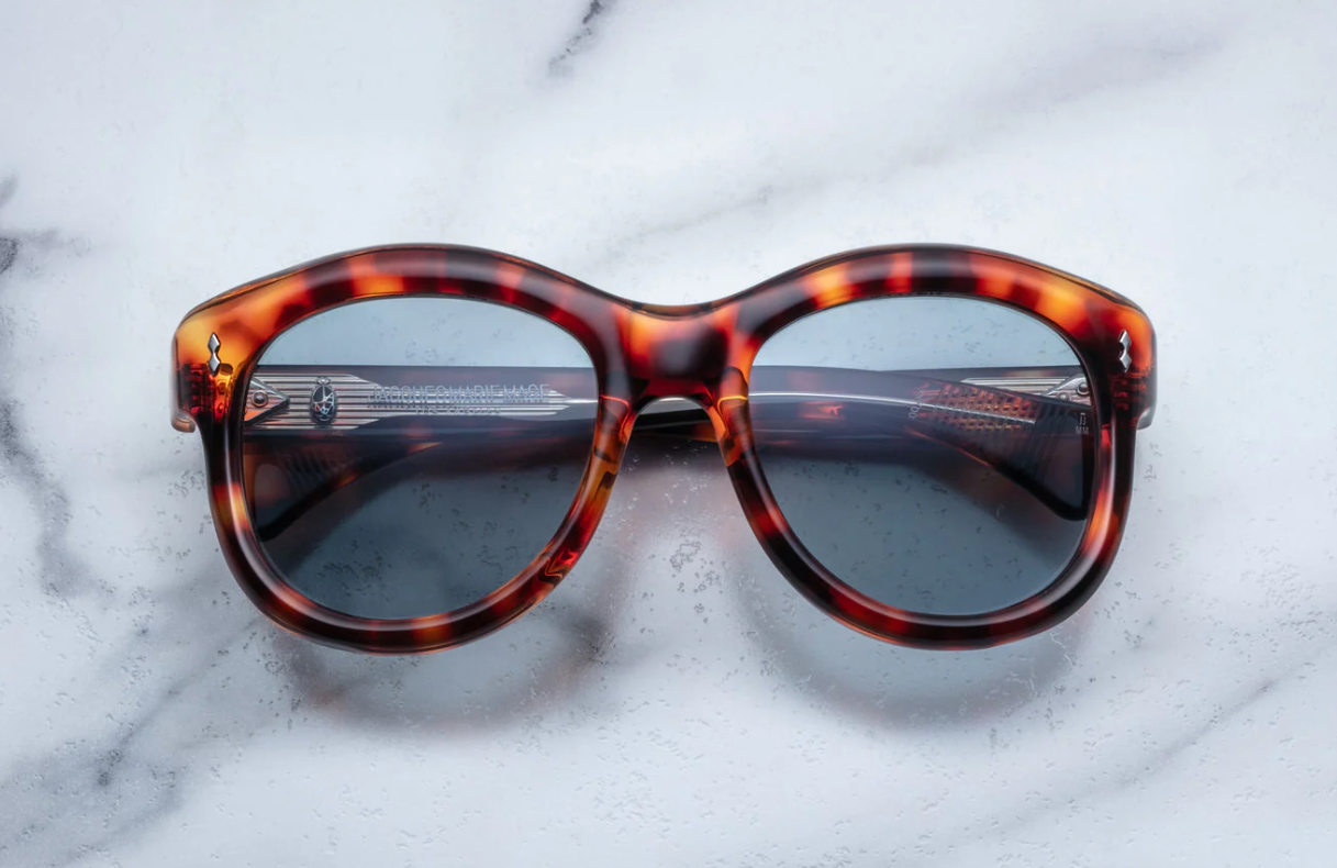 A pair of sunglasses with a leopard print frame, placed on a marble surface.