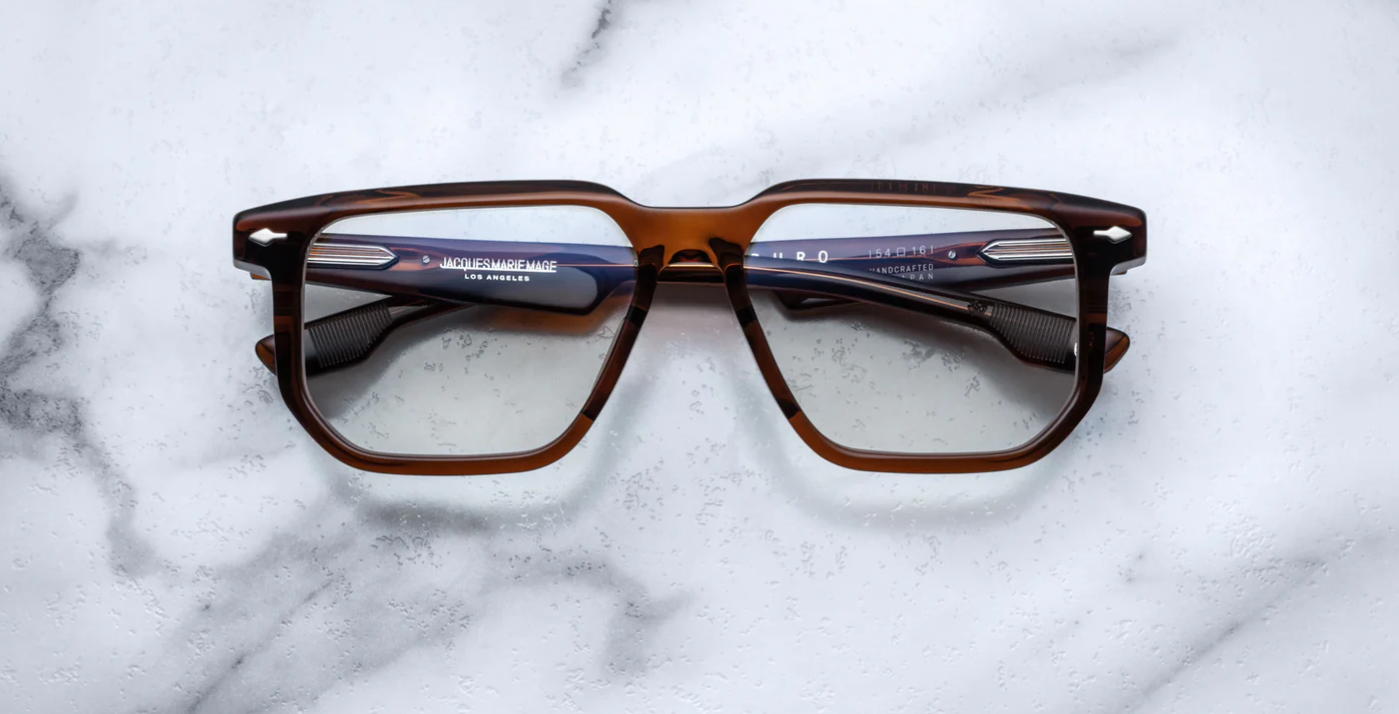 A pair of Jacques Marie Mage Saburo optical frames with a hickory color and navigator-style design, featuring handcrafted acetate and signature floating hinges.