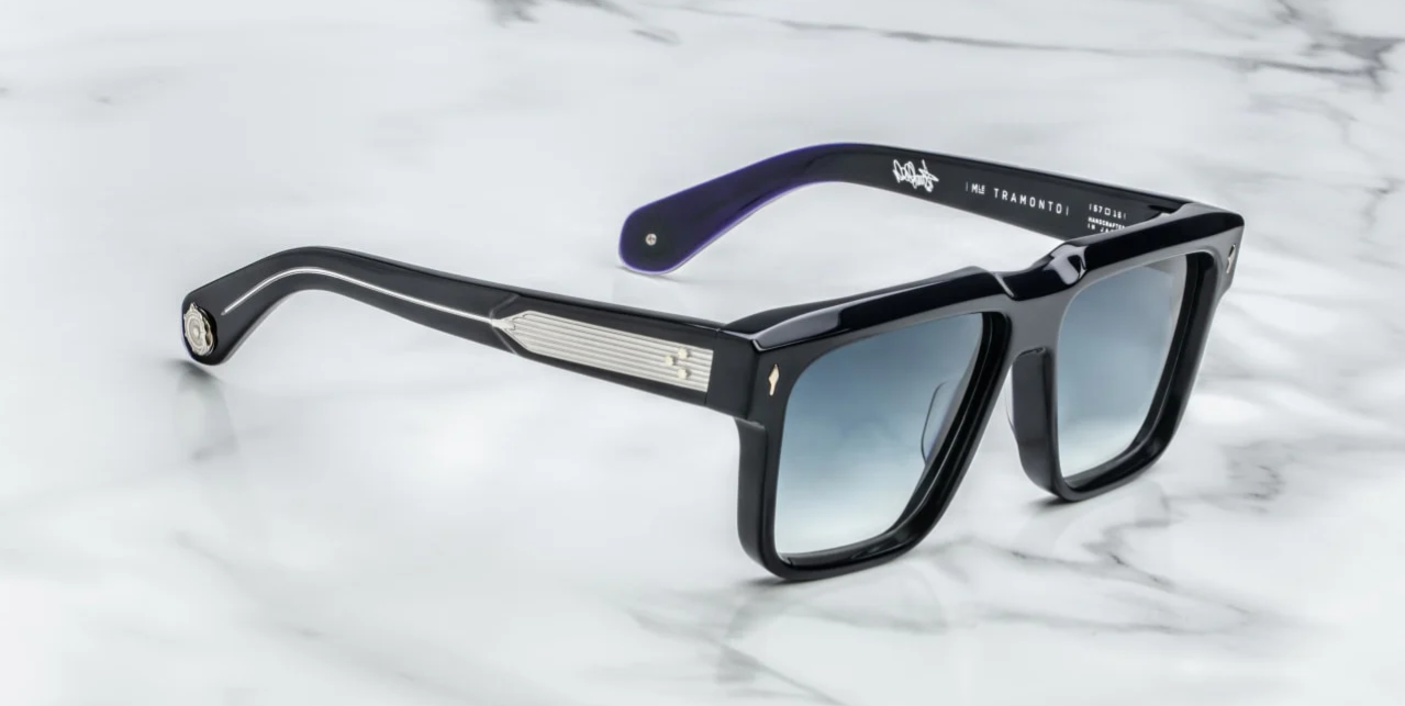 A pair of black rectangular framed sunglasses with a sculptural brow, resting on a marble surface.