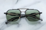 A pair of rimless sunglasses with a gunmetal frame, titanium nose-and-brow bridge, dual-tone details, sculptural acetate temples, and wirecore embellishments.