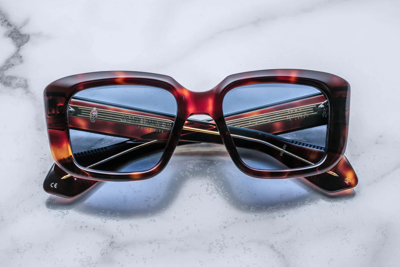 A pair of sunglasses with a Havana brown patterned frame on a marble surface.