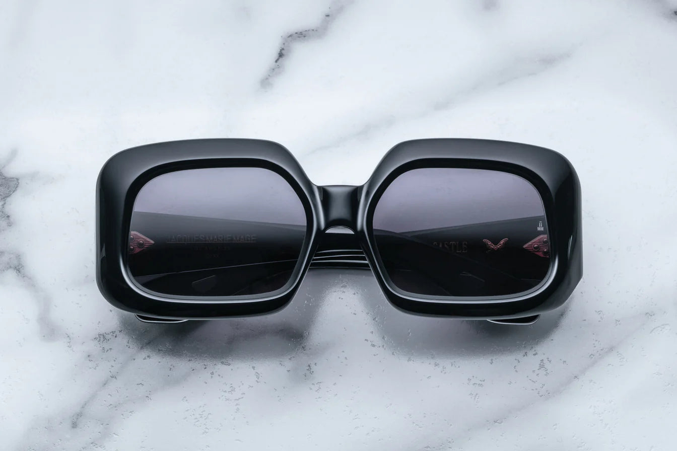 A pair of black, rectangular, '70s-inspired sunglasses with a marble background.