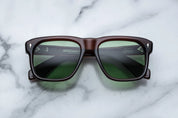 Sunglasses with brown frame and green lenses on a marble surface