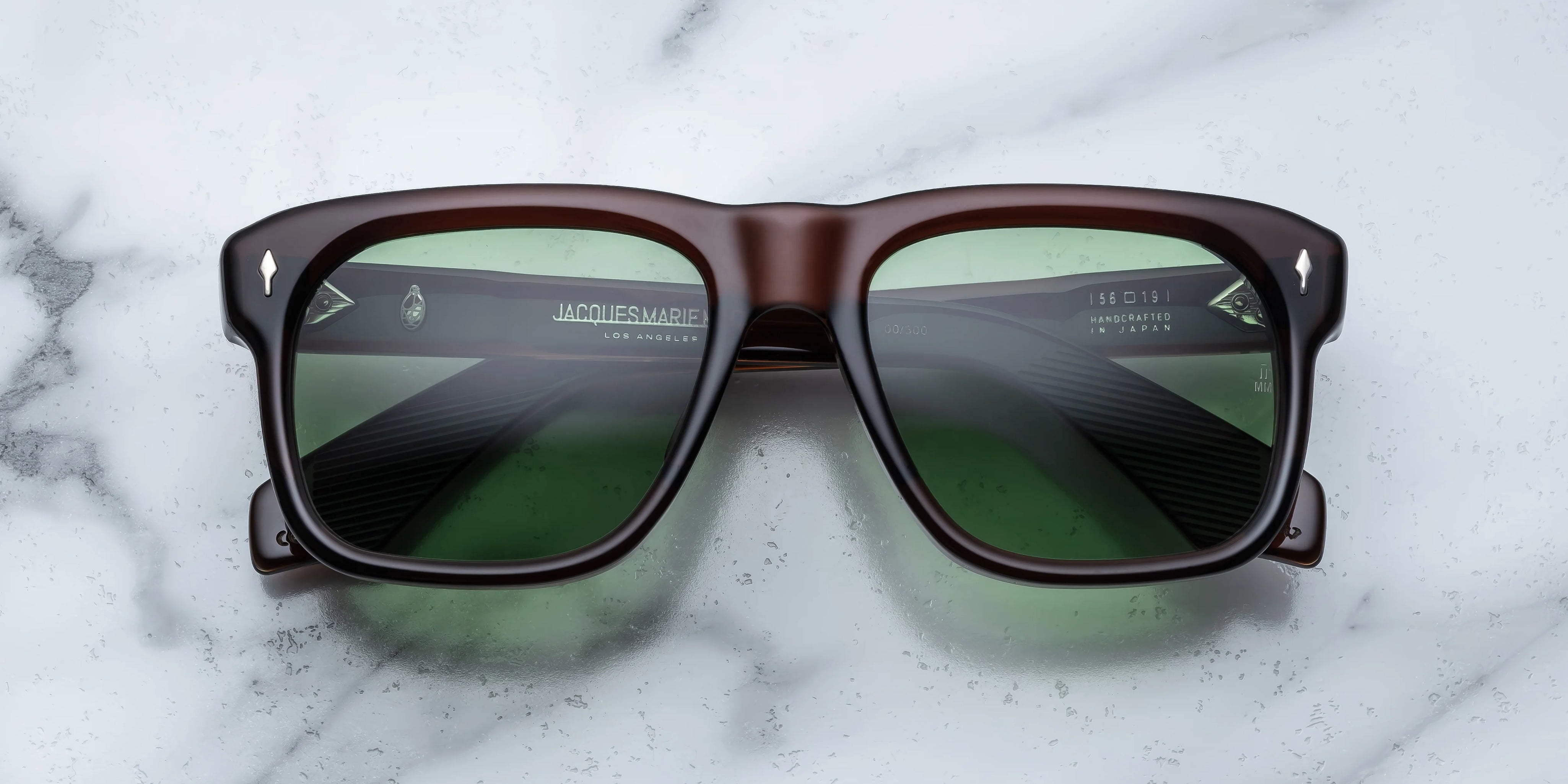 Sunglasses with brown frame and green lenses on a marble surface