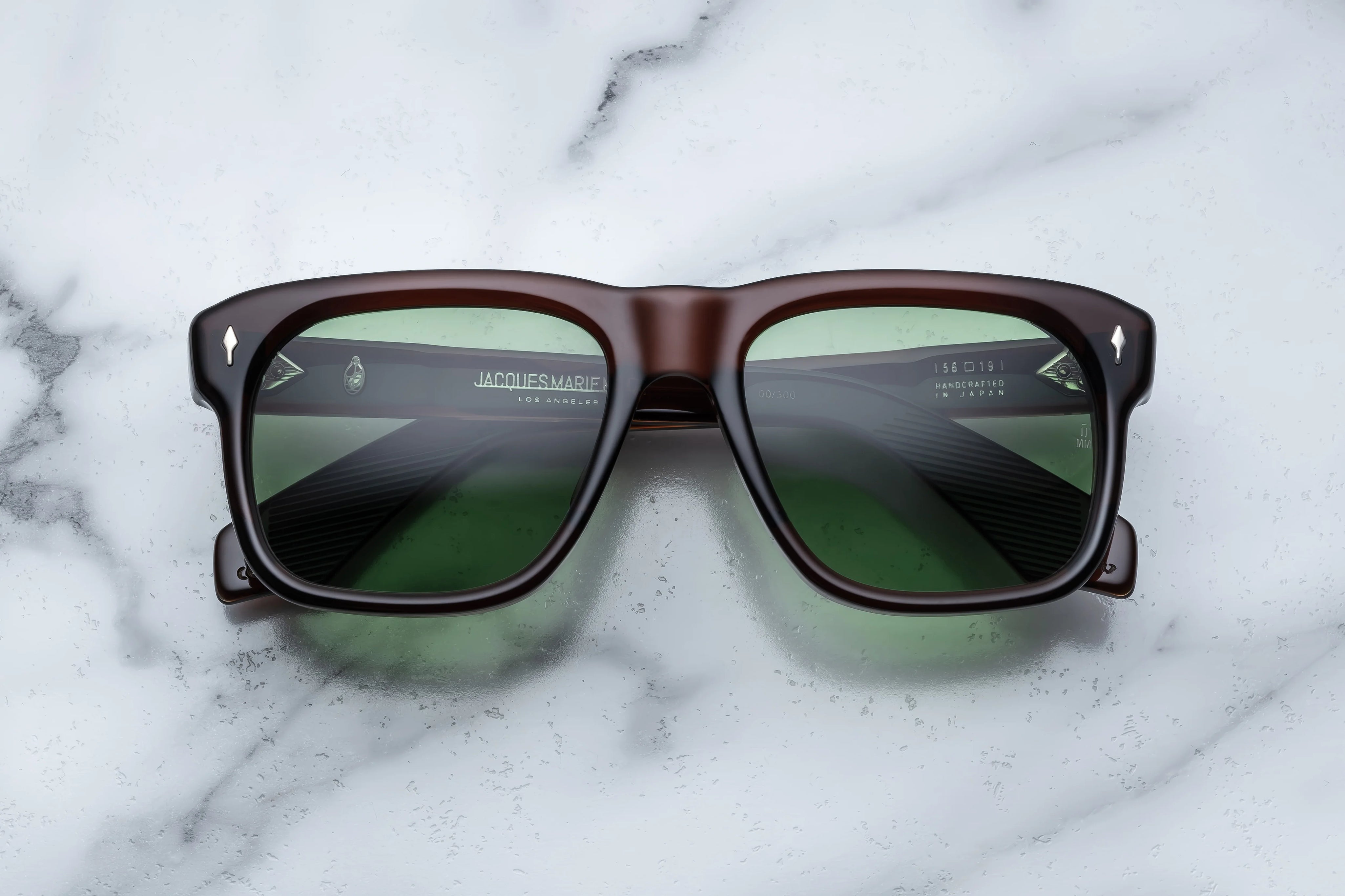 Sunglasses with brown frame and green lenses on a marble surface