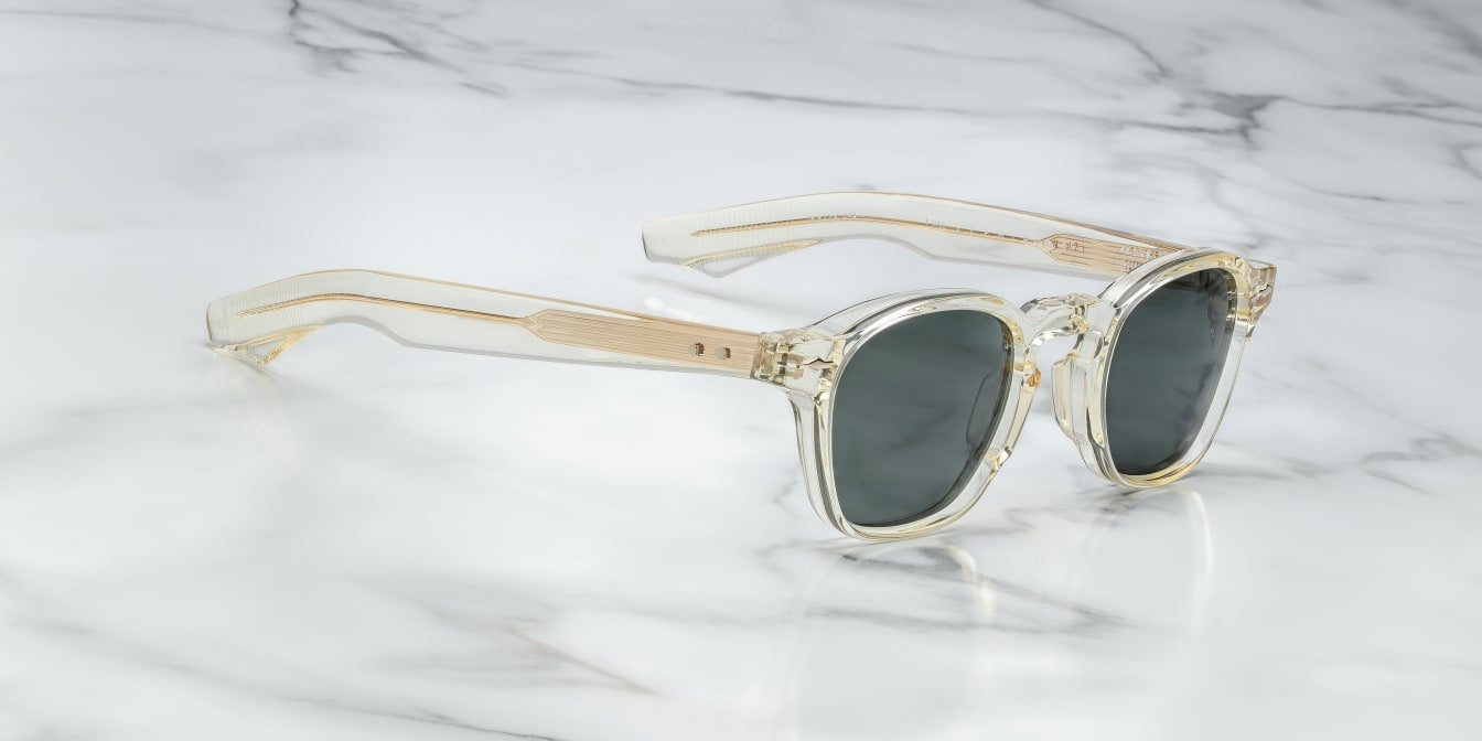 A pair of sunglasses with a distinctive frame, sculptural temples, and a sophisticated silhouette. The frame is notable for its slim lines in champgne side on view