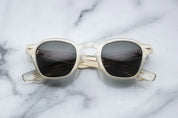 A pair of sunglasses with a distinctive frame, sculptural temples, and a sophisticated silhouette. The frame is notable for its slim lines in champgne 