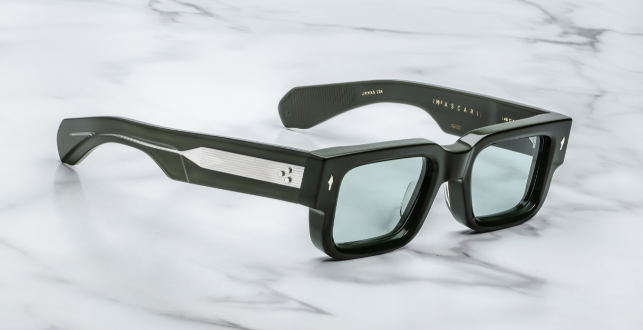 A pair of rectangular, dark green sunglasses with custom double-laminated temples and wirecores, on a marble surface. side view