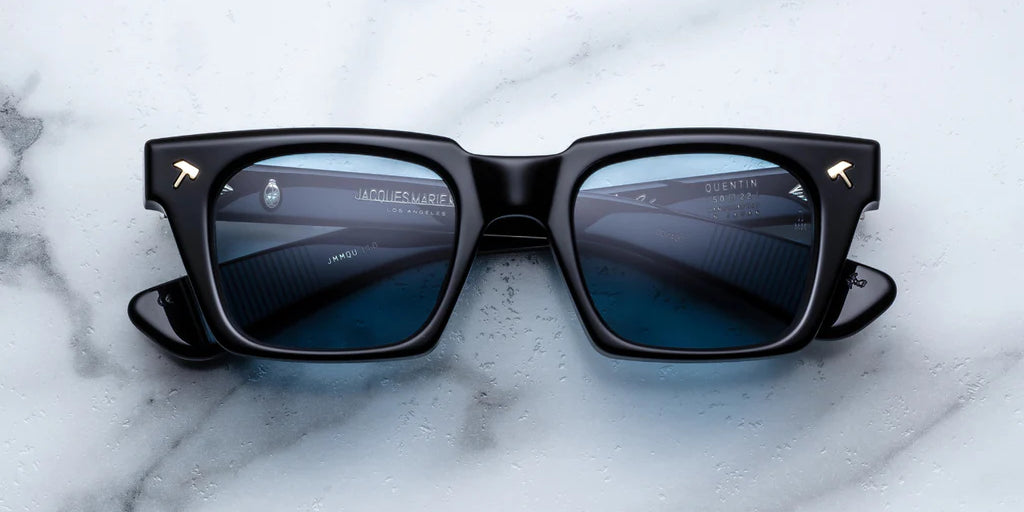 black sunglass front on with silver hammer detail on the corners and blue lenses