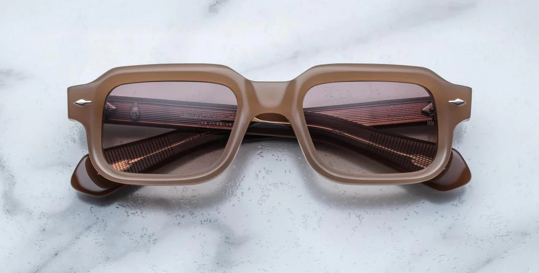 A pair of rectaunglar-shaped sunglasses with a brown frame, displayed on a marble surface.