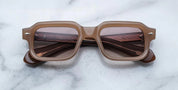 A pair of rectaunglar-shaped sunglasses with a brown frame, displayed on a marble surface.