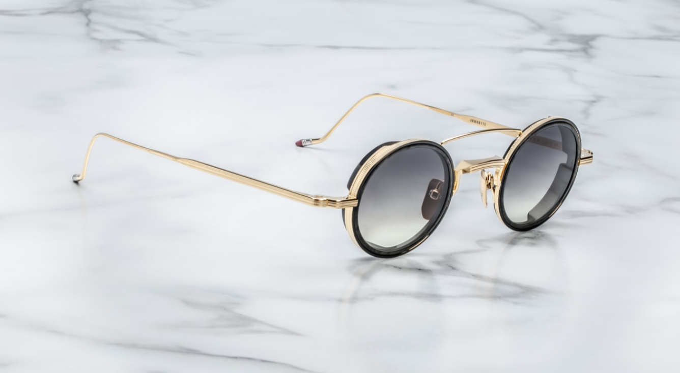 A pair of round full frame sunglasses with a double bridge design, acetate eye rim inserts, and hand-painted epoxy temple tips on a marble surface.